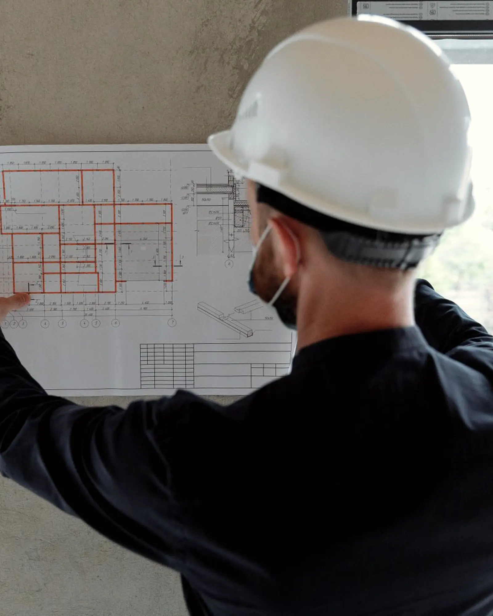 Profissional de capacete conferindo a planta na obra